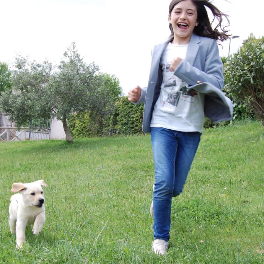 Bimba che corre nel campo con cucciolo